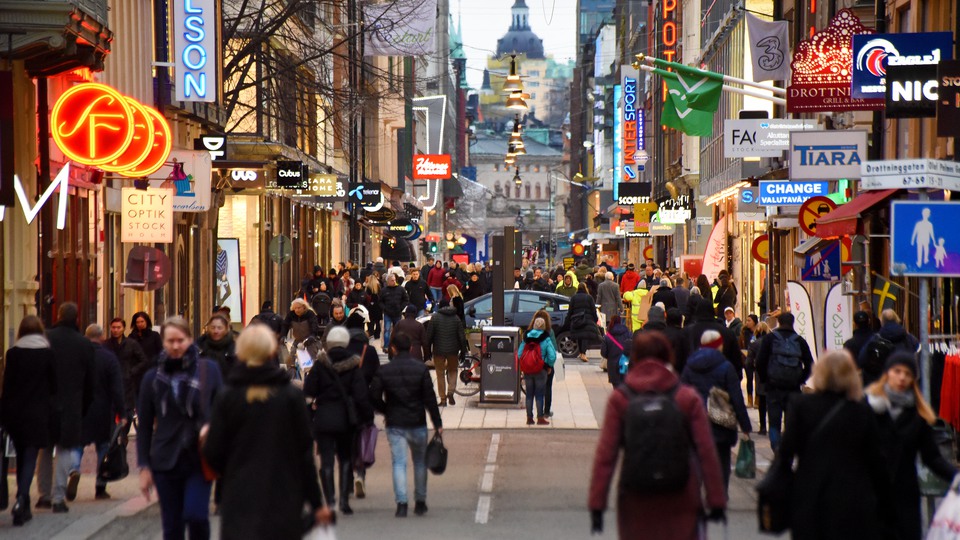Turister och stadsbor går längs en shoppinggata i Stockholm